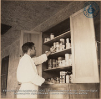 Aruban employee in Personnel Department checking over prices of sample canned goods purchased at random throughout the island stores for Cost-of-Living Survey (#5062, Lago , Aruba, April-May 1944), Morris, Nelson