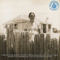Raymundo Feliciano's mother looking out over typical Aruban cactus fence surrounding the house (#5425, Lago , Aruba, April-May 1944), Morris, Nelson