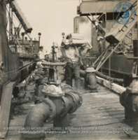Unloading vegetables from Venezuela, while the crude is being pumped out of the holds of the lake tankers (#12003, Lago , Aruba, April-May 1944), Morris, Nelson