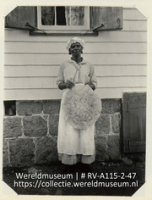 Portret van een lid van het huispersoneel voor het gouvernements logeerhuis op Saba met een vers bereide casavekoek (Collectie Wereldmuseum, RV-A115-2-47), De Goeje, C.H.