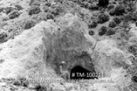 Zwavelmijnen op Saba. Ingang mijnschacht; De ingang van een wavelmijn, voor de ingang zit een man met een bijl (Collectie Wereldmuseum, TM-10021139)