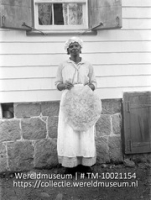 Negerin met cassavekoek, Saba; Portret van een vrouw in werkkleding met in haar hand een cassavekoek (Collectie Wereldmuseum, TM-10021154)
