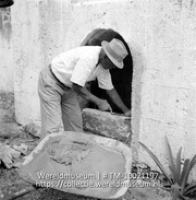 Dichtmetselen van een familiegraf na een begrafenis op het kerkhof van de ruine van de Nederlands Hervormde Kerk te St. Eustatius; Een man metselt een familie graf dicht ind e ruines van de kerk (Collectie Wereldmuseum, TM-10021197)