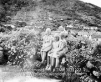 Saba. Schoolkinderen te Windwardside; Drie meisjes zitten op een stenen muur met op de achtergrond een stadsgezicht (Collectie Wereldmuseum, TM-10021327)