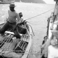 Vrachtgoederen voor Saba worden van het motor-zeiljacht de 'Blue Peter' overgedaan in een roeibootje, dat de goederen aan land brengt (Collectie Wereldmuseum, TM-10021357)