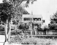 Saba. Het huis van de gezaghebber; Een grote woning met balkon geistueerd in een bergachtig landschap, voor het huis wappert een Nederlandse vlag (Collectie Wereldmuseum, TM-10021384)