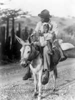 Watervervoer op Bonaire; Watervervoer per ezel, bereden door een man met kind (Collectie Wereldmuseum, TM-10021528)