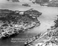 Curacao. Haven van Willemstad; op den achtergrond het Schottegat met petroleumraffinaderijen en tankschepen. (vogelvlucht); Luchtfoto van de haven van Willemstad en het Schottegat (Collectie Wereldmuseum, TM-10021698)