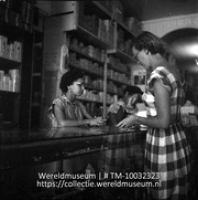 Een dame rekent af aan de toonbank in een winkel in Willemstad (Collectie Wereldmuseum, TM-10032323)