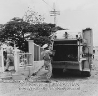 Vuilnisauto en twee medewerkers van de reinigingsdienst bij een tuinhek; Reinigingsdienst (Collectie Wereldmuseum, TM-20003776), Lawson, Boy