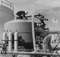Twee werknemers bij de drinkwaterinstallatie; Het toevoegen van chemicalien aan het drinkwater (Collectie Wereldmuseum, TM-20003781), Lawson, Boy