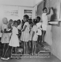 Kinderen bij de onderwijzer en schrijvend op het schoolbord, in een school voor lager onderwijs; School voor lager onderwijs (Collectie Wereldmuseum, TM-20003937), Lawson, Boy