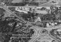 Luchtfoto van de rotonde op de kruising tussen de Rijkseenheidboulevard en de Schottegatweg, met op de achtergrond het Peter Stuyvesant College (Collectie Wereldmuseum, TM-60047600)