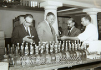 F. Karner; Mannen buigen zich in het landhuis Chobolobo over de Curacao likeur van de firma Senior & Co.; Men admiring the Curacao liqueur of the firm Senior & Co. at the Chobolobo country house (Collectie Wereldmuseum, TM-60060956)