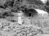Bakoven op Saba; Een vrouw is aan het bakken in een stenen uiten oven (Collectie Wereldmuseum, TM-10021121)