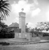 Een monument met een plaquette en bovenop een windwijzer in de vorm van een schip, opgericht ter gelegenheid van het 50 jarig regerings jubileum van Koningin Wilhelmina (Collectie Wereldmuseum, TM-10021231)
