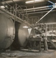 Man, wearing safety equipment, testing sulphuric acid being manufactured at Acid Contact Plant (#4966, Lago , Aruba, April-May 1944), Morris, Nelson