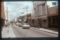 Nassaustraat (Main Street) met o.a. de winkels van Van Dorp, Disneyland, Checkpoint Color, Bon Bini Bazaar, Caribbean Mercantile Bank (CMB) en Aruba Sunshine Restaurant, 1976, Vredebregt, Casper