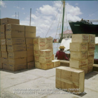 Opgestapelde stukgoederen op de kade van een haven (Collectie Wereldculturen, TM-20029501), Lawson, Boy (1925-1992)